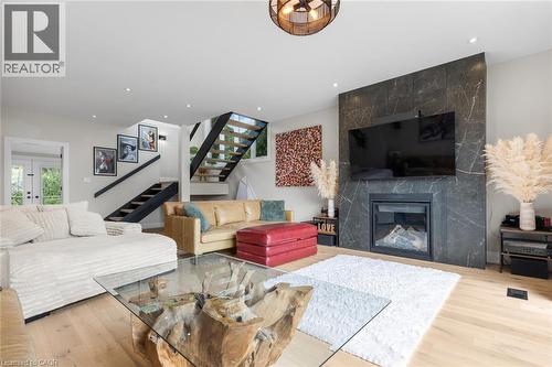 Hardwood-style flooring, recessed lighting, and a modern fireplace with a dark stone surround - 293 North Shore Boulevard E, Burlington, ON 