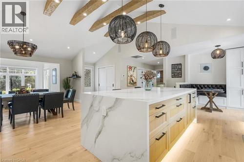 Vaulted ceilings with exposed beams, wood-finish flooring, waterfall island with a light-toned countertop, custom built-in seating, and modern pendant lighting - 293 North Shore Boulevard E, Burlington, ON 
