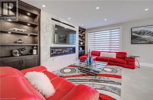 Living room with horizontal gas fireplace accented with built-in shelves - 61 Schweitzer Street, Kitchener, ON 