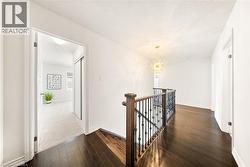 Hallway featuring an upstairs landing, dark wood finished floors, and a chandelier - 