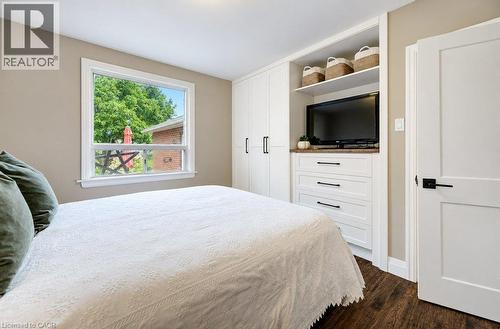 White built-in cabinetry, integrated shelving, wood-finish countertop, dark wood-finish flooring, and a white interior door with black hardware - 37 Margaret Avenue N, Waterloo, ON 