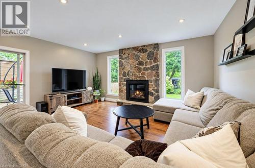 Stone-faced fireplace, recessed ceiling lighting, wood-finish flooring, and a sliding glass door to the exterior - 37 Margaret Avenue N, Waterloo, ON 
