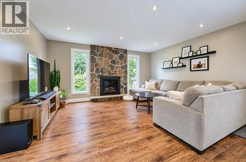 Stone-clad fireplace with a hearth, wood-finish flooring, recessed lighting, and dual vertical windows - 37 Margaret Avenue N, Waterloo, ON 