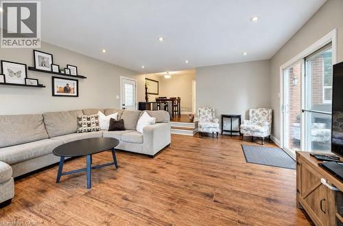 Spacious living area featuring wood-finish flooring, recessed lighting, and a sliding glass door - 37 Margaret Avenue N, Waterloo, ON 