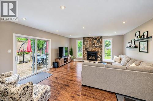 Wood-finish flooring throughout, featuring a stone-faced fireplace, recessed lighting, and white trim windows - 37 Margaret Avenue N, Waterloo, ON 