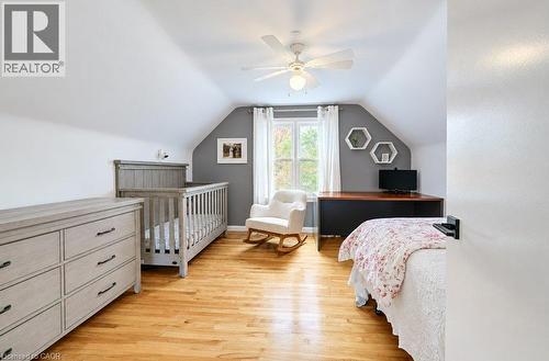 Hardwood flooring, sloped ceiling, window with white curtains, ceiling fan with light fixture, built-in desk with wood-finish top - 37 Margaret Avenue N, Waterloo, ON 