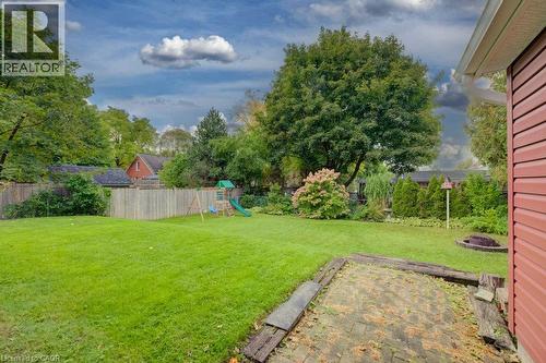 Expansive green lawn with mature trees, wood fence, and a paver patio with a wood border - 37 Margaret Avenue N, Waterloo, ON 
