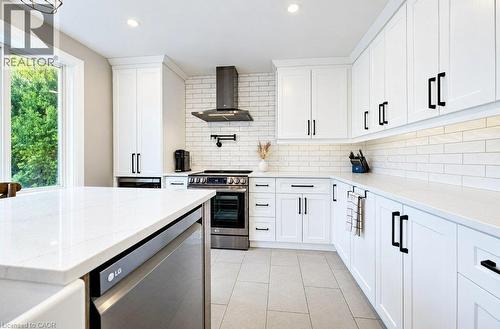 White shaker-style cabinetry with matte black hardware, light-toned countertops, subway tile backsplash, stainless steel appliances, and large format floor tile - 37 Margaret Avenue N, Waterloo, ON 