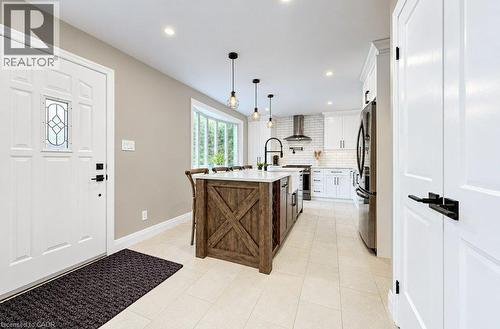 Kitchen featuring a wood-finish island with a white countertop, white shaker cabinetry, stainless steel appliances, and subway tile backsplash - 37 Margaret Avenue N, Waterloo, ON 