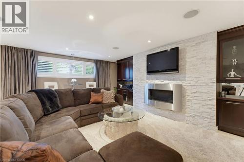 Recreation room with fireplace, TV and wall units flanking both sides. - 77 Yellow Birch Drive, Kitchener, ON 