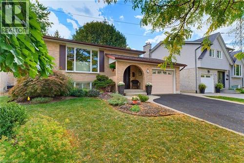Brick exterior with an arched entryway, attached garage, and paved driveway - 77 Yellow Birch Drive, Kitchener, ON 