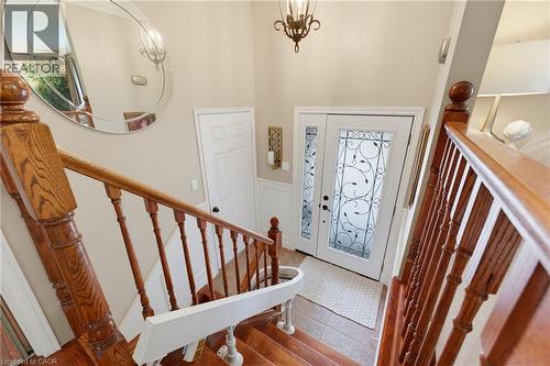 Wood-finish staircase with turned balusters, front door with transom window. - 77 Yellow Birch Drive, Kitchener, ON 