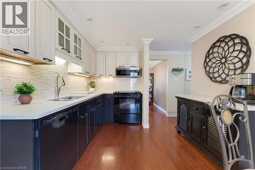Kitchen featuring white upper cabinetry, dark lower cabinetry and hardwood flooring. - 77 Yellow Birch Drive, Kitchener, ON 