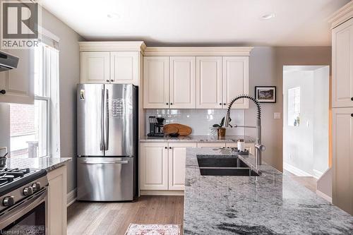 The eat-in kitchen is complemented by a bright dining room/home office combination, featuring a cozy fireplace and walkout to the large deck and beautifully landscaped backyard. - 132 Herkimer Street, Hamilton, ON 