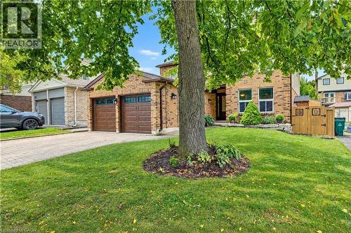 Brick exterior with dual garage doors, a paved driveway, and manicured landscaping - 104 Deerwood Crescent, Kitchener, ON 
