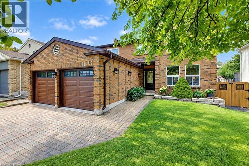 Brick facade with a two-car garage featuring paneled doors - 104 Deerwood Crescent, Kitchener, ON 
