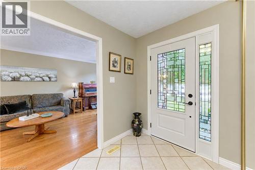 White paneled front door with decorative glass inserts, side-light window with decorative glass, and a black handle set - 104 Deerwood Crescent, Kitchener, ON 