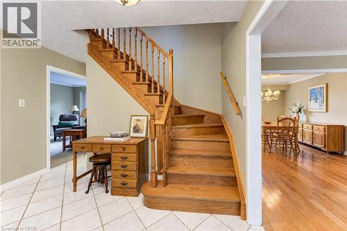 Hardwood staircase with traditional balusters, tile flooring, and a wide entryway - 104 Deerwood Crescent, Kitchener, ON 