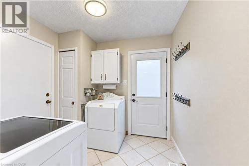 White upper cabinetry, tiled flooring, and a frosted pane door - 104 Deerwood Crescent, Kitchener, ON 