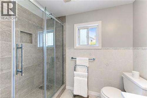 Glass-enclosed shower with gray tiled walls and a built-in niche - 104 Deerwood Crescent, Kitchener, ON 