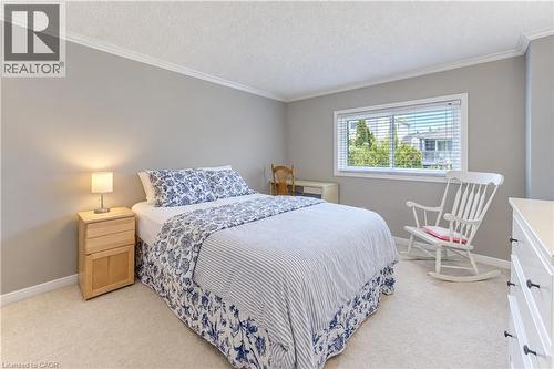 Light gray wall color, white crown molding, white window trim, textured ceiling, and light-toned carpeting - 104 Deerwood Crescent, Kitchener, ON 