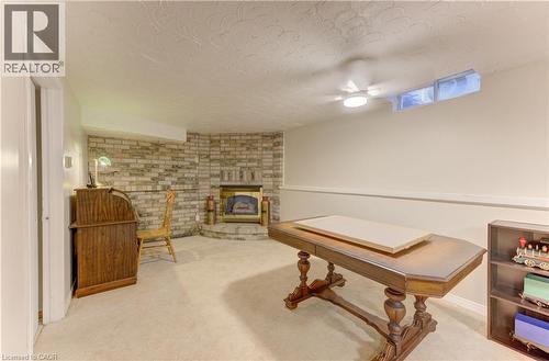 Brick accent wall with a built-in fireplace, carpeted flooring, and a ceiling-mounted light fixture - 104 Deerwood Crescent, Kitchener, ON 