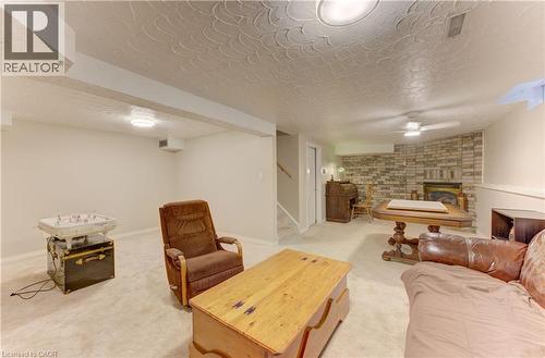 Carpeted flooring throughout, recessed lighting fixtures, ceiling fan with light, and a brick-finish fireplace - 104 Deerwood Crescent, Kitchener, ON 