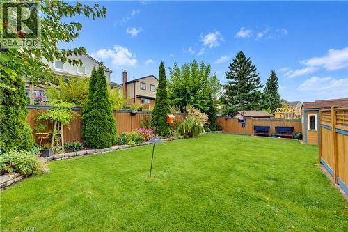 Expansive lawn area, perimeter fencing, mature trees, landscaped planting beds, and a storage shed - 104 Deerwood Crescent, Kitchener, ON 