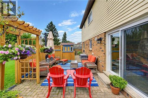 Brick paver patio with a wooden pergola, privacy fencing, and sliding glass door access - 104 Deerwood Crescent, Kitchener, ON 
