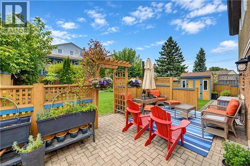 Paver patio with a wood privacy fence, decorative trellis, and a detached storage shed - 104 Deerwood Crescent, Kitchener, ON 