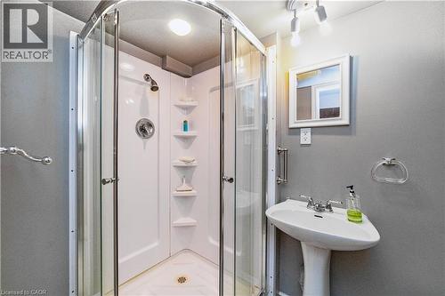 Corner shower enclosure with glass doors, pedestal sink, wall-mounted mirror, and overhead track lighting - 41 Tuerr Drive, Kitchener, ON 