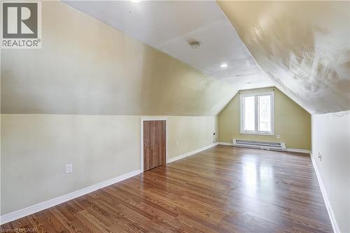 Sloped ceiling room featuring wood-finish flooring, a double window, and recessed lighting - 11 Elm Street, Hamilton, ON 