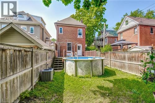 Fenced backyard with an above-ground pool, brick exterior, and wood deck - 11 Elm Street, Hamilton, ON 
