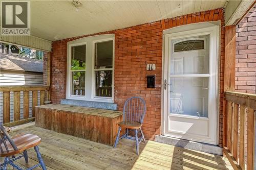 Covered wood-plank porch with brick wall siding, wood railing, and white-framed windows - 11 Elm Street, Hamilton, ON 