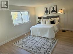 Light wood-finish flooring, white trim, and a window with white casing - 