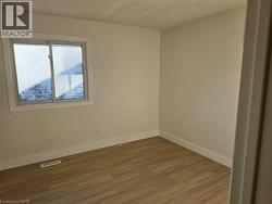 Neutral wall paint, wood-finish flooring, white trim, and a sliding window - 