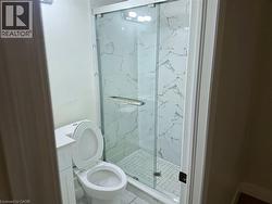 Shower with glass enclosure, white tile surround, and mosaic tile shower floor - 