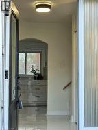 Entryway featuring a decorative transom, a contemporary ceiling light fixture, polished tile flooring, and a wooden handrail - 