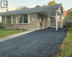 Brick exterior with a peaked roofline, featuring a covered carport, paved driveway, and a front walkway - 