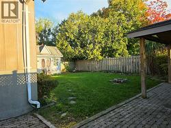 Expansive backyard featuring a manicured lawn, established privacy fencing, and a built-in storage shed - 