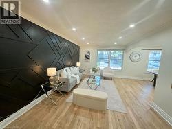 Accent wall with geometric paneling, recessed lighting, crown molding, light wood-finish flooring, and multiple windows - 
