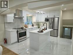 Modern kitchen featuring high-gloss white cabinetry, stainless steel appliances, a center island with a black gooseneck faucet, and white marble-look floor tile - 