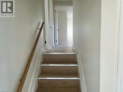 Staircase with wood-finish treads, light-toned walls, and a wooden handrail - 