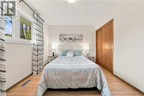 Wood-finish flooring, white walls, white window trim, and a built-in closet with wood doors - 662 Dynes Road, Burlington, ON 