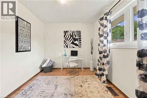 Wood-finish flooring with white baseboards, a single window, and a ceiling-mounted light fixture - 662 Dynes Road, Burlington, ON 
