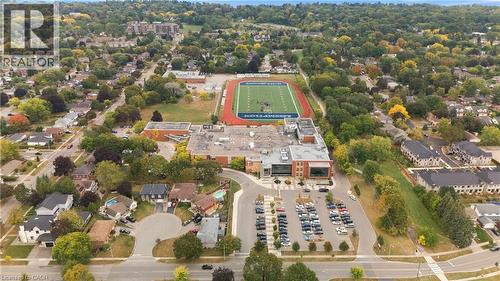 Aerial perspective of a developed neighborhood featuring residential properties, mature trees, and a school building with an athletic field - 662 Dynes Road, Burlington, ON 
