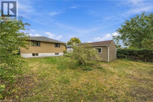 Expansive yard featuring a separate outbuilding, mature perimeter landscaping, and a brick-clad residence with a shingled roof - 662 Dynes Road, Burlington, ON 