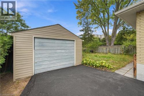 Detached garage with horizontal siding, asphalt driveway, and a fenced yard with mature trees - 662 Dynes Road, Burlington, ON 
