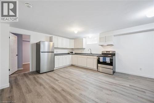 Open-concept kitchen with white cabinetry, dark countertops, stainless steel appliances, and wood-finish flooring - 233 Dearborn Boulevard Unit# Lower, Waterloo, ON 