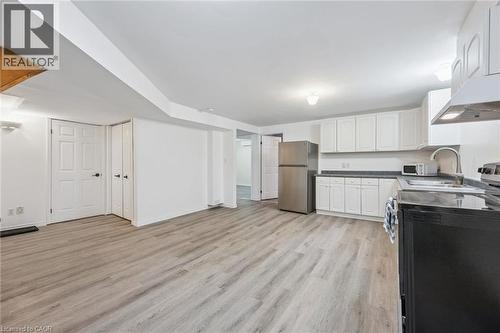 Wood-finish flooring throughout, white cabinetry, stainless steel refrigerator, and ample counter space - 233 Dearborn Boulevard Unit# Lower, Waterloo, ON 